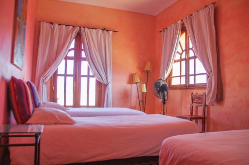 a bedroom with two beds and two windows at Dar Essaada in Essaouira