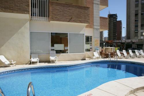 una gran piscina con sillas y un edificio en Apartamentos Benimar - SABESA, en Benidorm