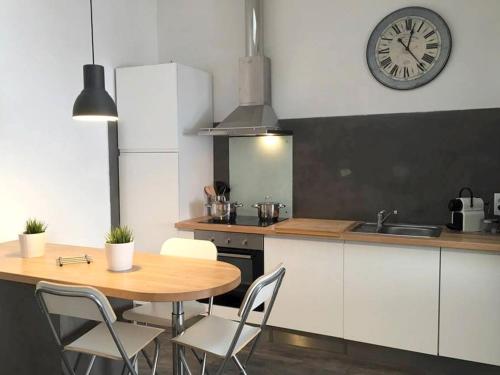 une cuisine avec une table et une horloge au mur dans l'établissement cite 4 Maison Bacou, à Carcassonne