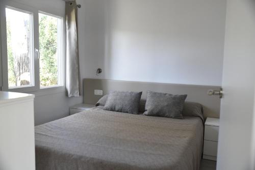 a white bedroom with a bed with two pillows at Alannia Guardamar in Guardamar del Segura