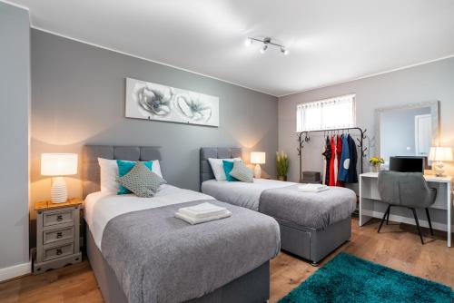 - une chambre avec deux lits, un bureau et une chaise dans l'établissement Large Apartment Near Stonehenge Amesbury Town Centre Smart TVs Netflix FREE PARKING, à Amesbury