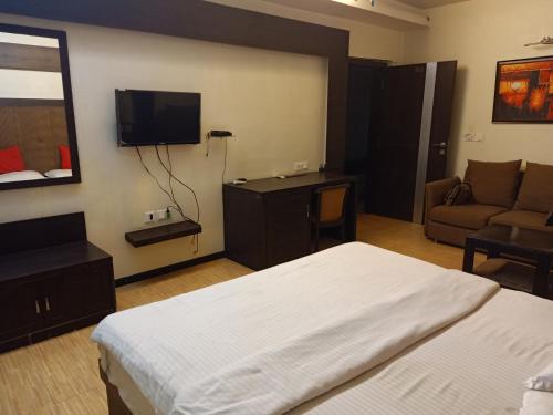 ein Schlafzimmer mit einem Bett, einem Sofa und einem TV in der Unterkunft Hotel V.I.P. Regency in Dhanbad