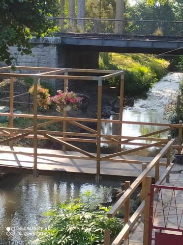 a wooden bridge over a river with flowers on it at Chambres d'hotes du Port Gautier in Vouvray-sur-Loir