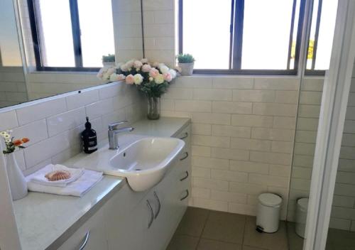 a bathroom with a sink and a vase of flowers at Vista Marina Penthouse #5 - Amazing views & location in Bermagui