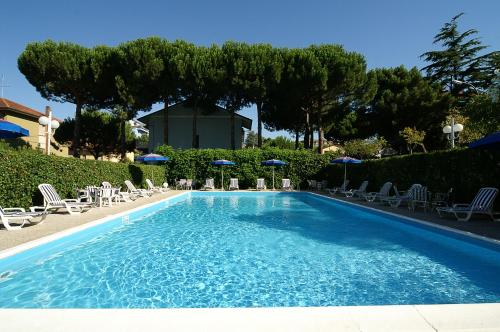 una gran piscina azul con sillas y sombrillas en Hotel Casali, en Cervia