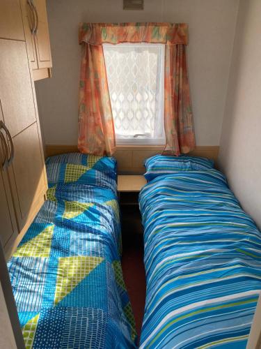 two beds in a small room with a window at Eastgate Fantasy Islands Static Caravan Park in Ingoldmells