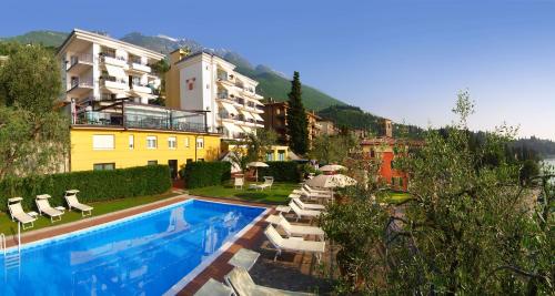 un hotel con piscina, sillas y un edificio en Hotel Capri, en Malcesine