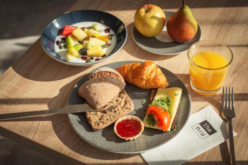 a table with two plates of breakfast foods and a glass of orange juice at Holiday Inn - the niu, Coin Frankfurt Ostend by IHG in Frankfurt/Main