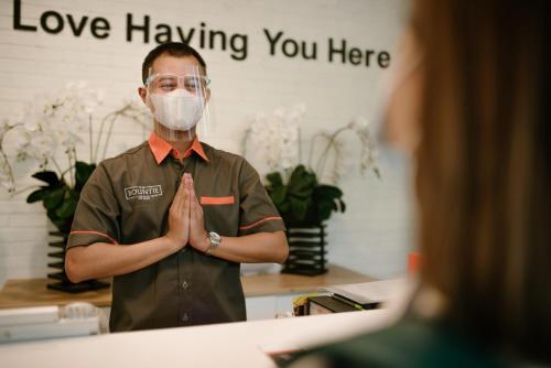 a man wearing a mask praying in front of a mirror at The Bountie Hotel and Convention Centre Sukabumi in Sukabumi