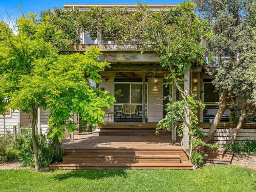 a house with a porch with trees in front of it at The Deck House in Smiths Beach