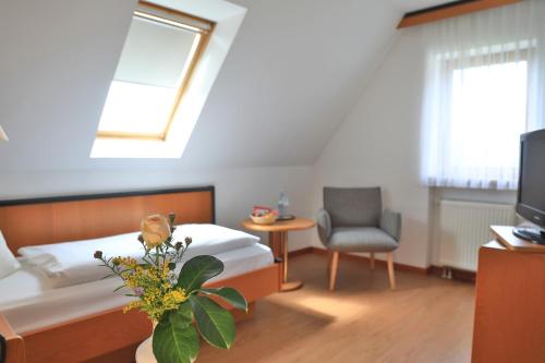 a bedroom with a bed and a chair and a tv at Landidyll Hotel Zum Alten Schloss in Kirchensittenbach