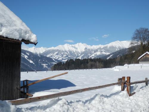 a snow covered field with a fence and mountains at Ferienhaus Maier in Lind