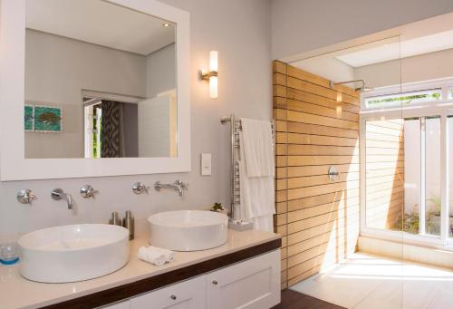 uma casa de banho com 2 lavatórios e um espelho em Four Rosmead Boutique Guesthouse em Cidade do Cabo