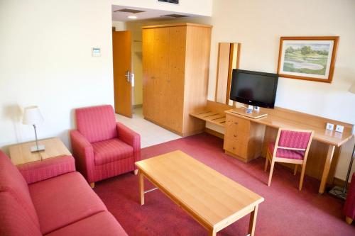a living room with a couch and a tv and chairs at Amazonia Palmela Apartamentos Turisticos in Palmela