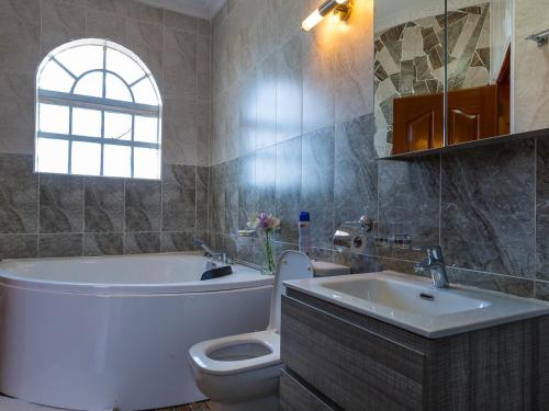 a bathroom with a tub and a toilet and a sink at Comfort Gardens Sweetwaters in Nanyuki