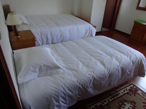 two beds with white sheets in a room at Hospedaria Lampião in Penacova