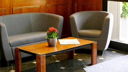 Dos sillas y una mesa con un jarrón de flores. en Hotel Ilbertz Garni en Colonia