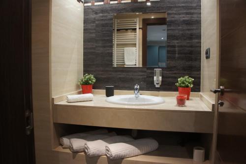 a bathroom with a sink and a mirror and towels at Arizonica Suites in Madrid