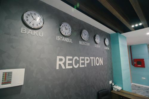 a wall with clocks on it with the words baku and reception at Tour-ZamZam-Madinah Halal Hotels Group in Baku