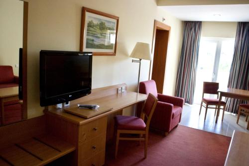 a hotel room with a television on a desk with chairs at Amazonia Palmela Apartamentos Turisticos in Palmela
