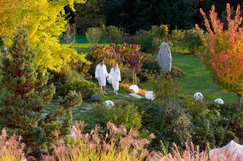 two women in white walking through a garden at Hotel Panorama Royal in Bad Häring