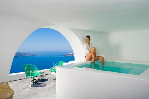 a man is sitting in a pool of water at Sophia Luxury Suites in Imerovigli