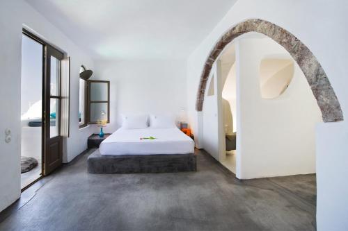 a bedroom with a white bed and an archway at Sophia Luxury Suites in Imerovigli