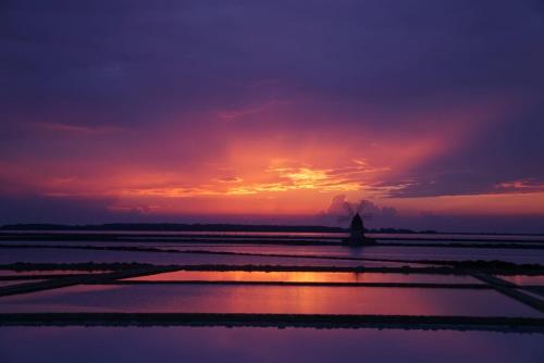 a sunset over the water with a statue in the distance at Romeo&giuliet in Marsala
