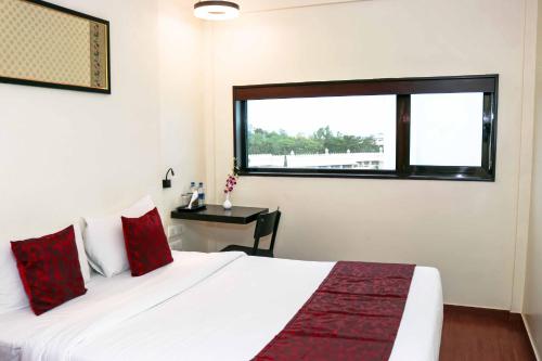 una camera da letto con un letto bianco con cuscini rossi e una finestra di 7 Apple Hotel Aurangabad ad Aurangabad