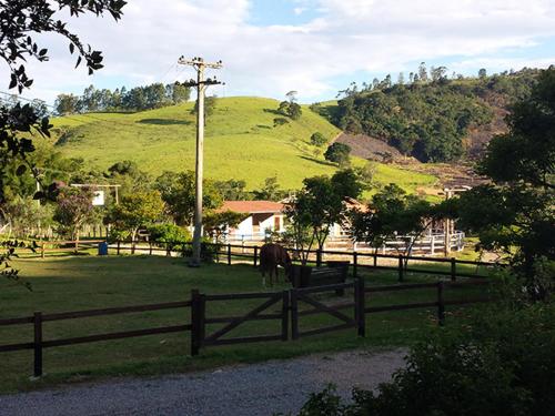 a horse standing in a field behind a fence at Pousada Recanto da Siriema in Monte Alegre do Sul