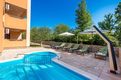 a pool with chairs and umbrellas next to a house at Villa Romana and Tea in Šilo