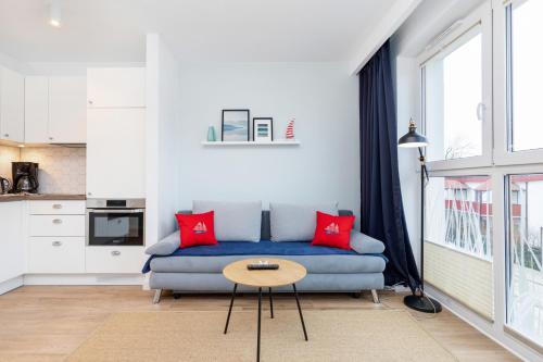 a living room with a blue couch and red pillows at Marine Apartment 9B by Renters in Dziwnówek