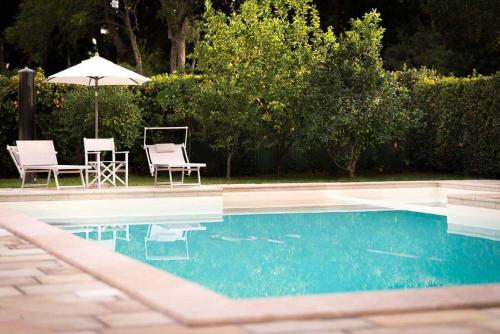a swimming pool with two chairs and an umbrella at Casale la Crocetta in Rosignano Solvay