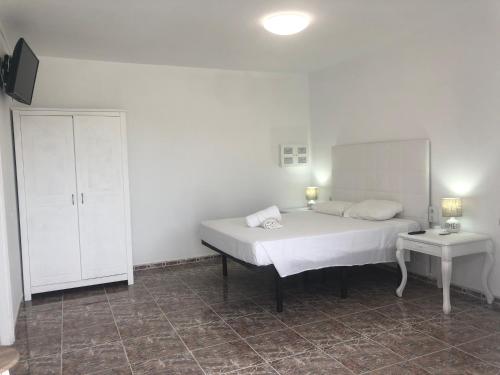 a bedroom with a white bed and a white cabinet at Apartamentos Elena in Lajares