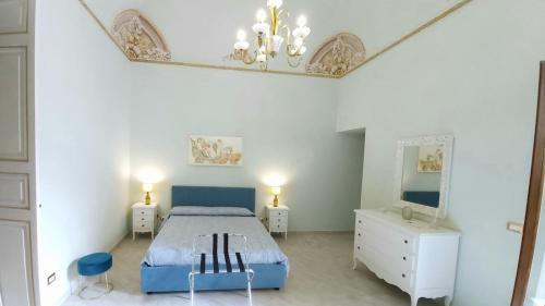 a white bedroom with a blue bed and a mirror at i 2 Capitani in Riposto