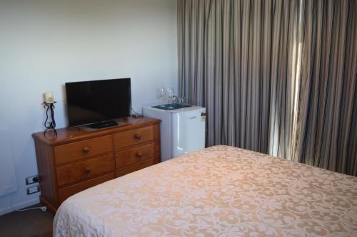 a bedroom with a bed and a tv and a dresser at Bed & Breakfast in the Heart of Fendalton in Christchurch