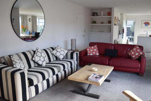 a living room with a red couch and a table at Bed & Breakfast in the Heart of Fendalton in Christchurch