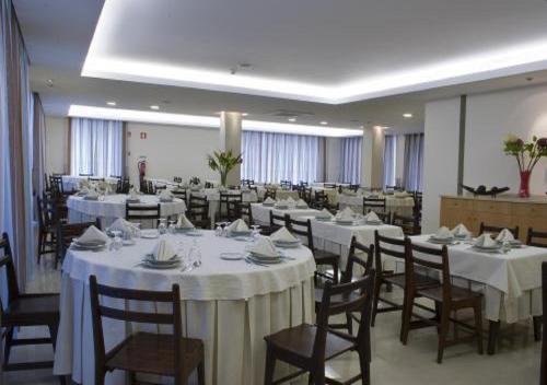 a banquet hall with white tables and chairs at Hotel Santo Condestavel in Fátima