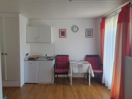 a kitchen with a table and two red chairs and a table at Gästehaus Steuer in Kröv