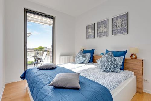 NORDBYHUS Apartamenty Garden Gates في غدانسك: غرفة نوم بسرير ازرق وبيض ونافذة