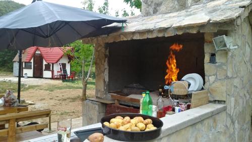 a fire pit with a bowl of potatoes and an umbrella at Krka Fairytale village in Rupe