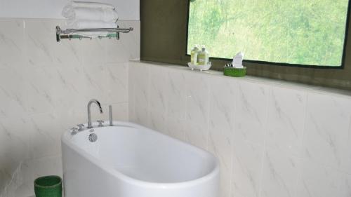ein weißes Bad mit einem Waschbecken und einem Fenster in der Unterkunft Osero Lodge in Ololaimutiek