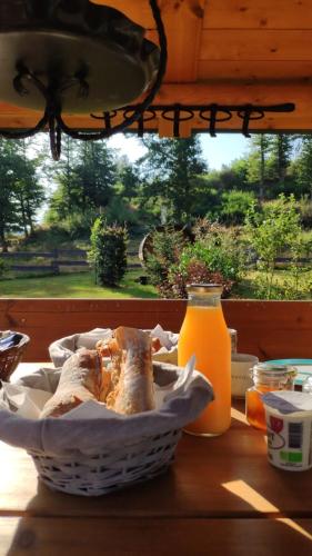 un panier de pain assis sur une table avec un verre de jus d'orange dans l'établissement Ma roulotte sous les chênes- Au naturel, à Raon-aux-Bois
