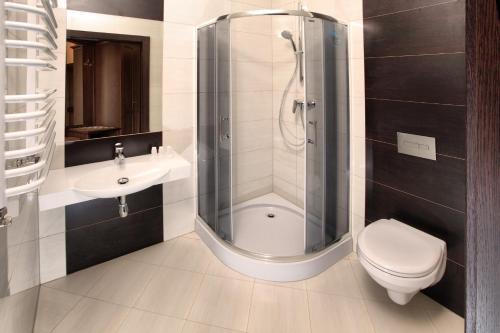a bathroom with a shower and a toilet and a sink at The Amber Business & Spa Hotel in Oleśnica