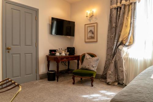 1 dormitorio con escritorio, silla y TV en The Coach and Horses, en Clitheroe