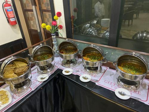 a buffet with four pots of food on a table at City Centre Suites in Multan