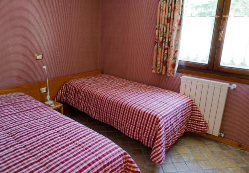 two beds in a room with red and white sheets at Suite sulle piste in Faidello