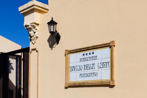 a sign on the side of a building with a lamp at Hotel Foresteria Baglio Della Luna in San Leone