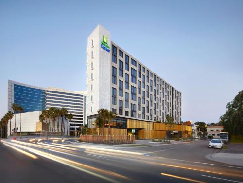 a tall white building with a car driving down a street at Holiday Inn Express Sydney Airport, an IHG Hotel in Sydney