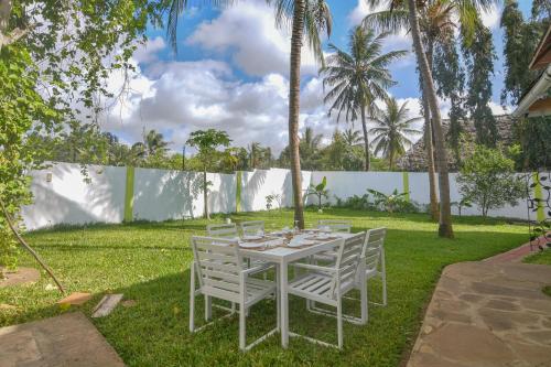 a white table with white chairs in a yard at Villa Ameera Malindi in Malindi